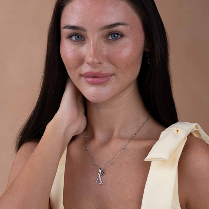 Woman wearing a necklace with a pendant against a beige background